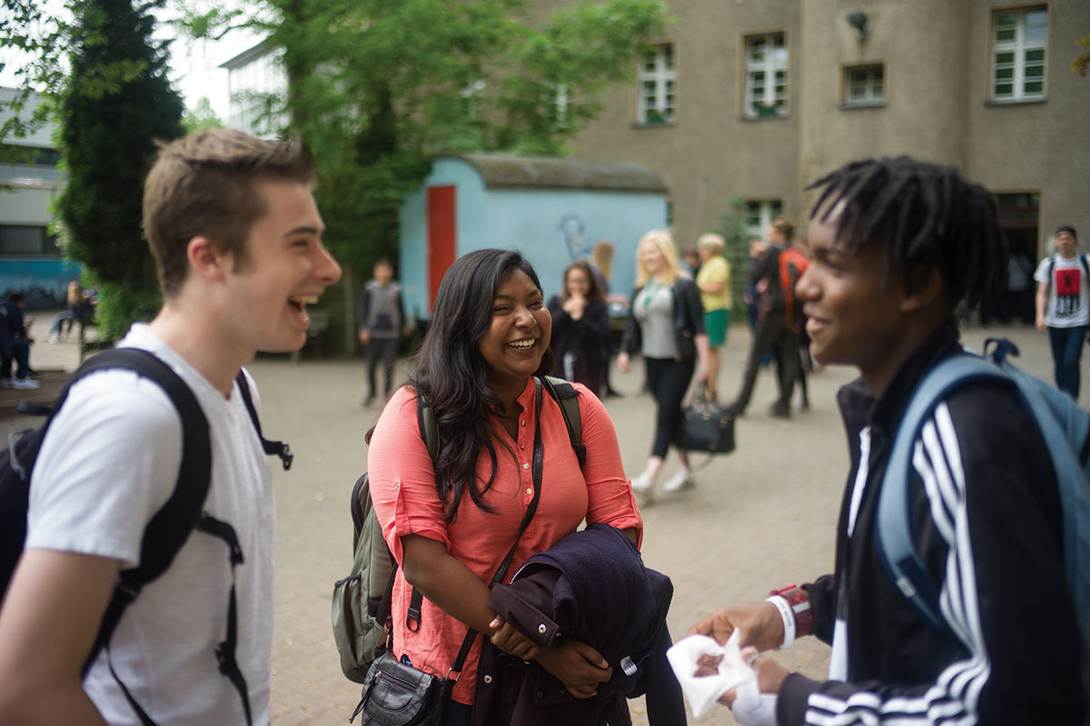 UM students Sachi Sinhara, center, and Arno, left, talk with a student at Berlin’s Johanna-Eck School. The school has made headlines for its successful approach to integrating refugees into the community.