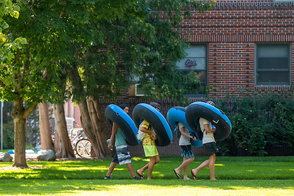 Students holding river tubes on campus