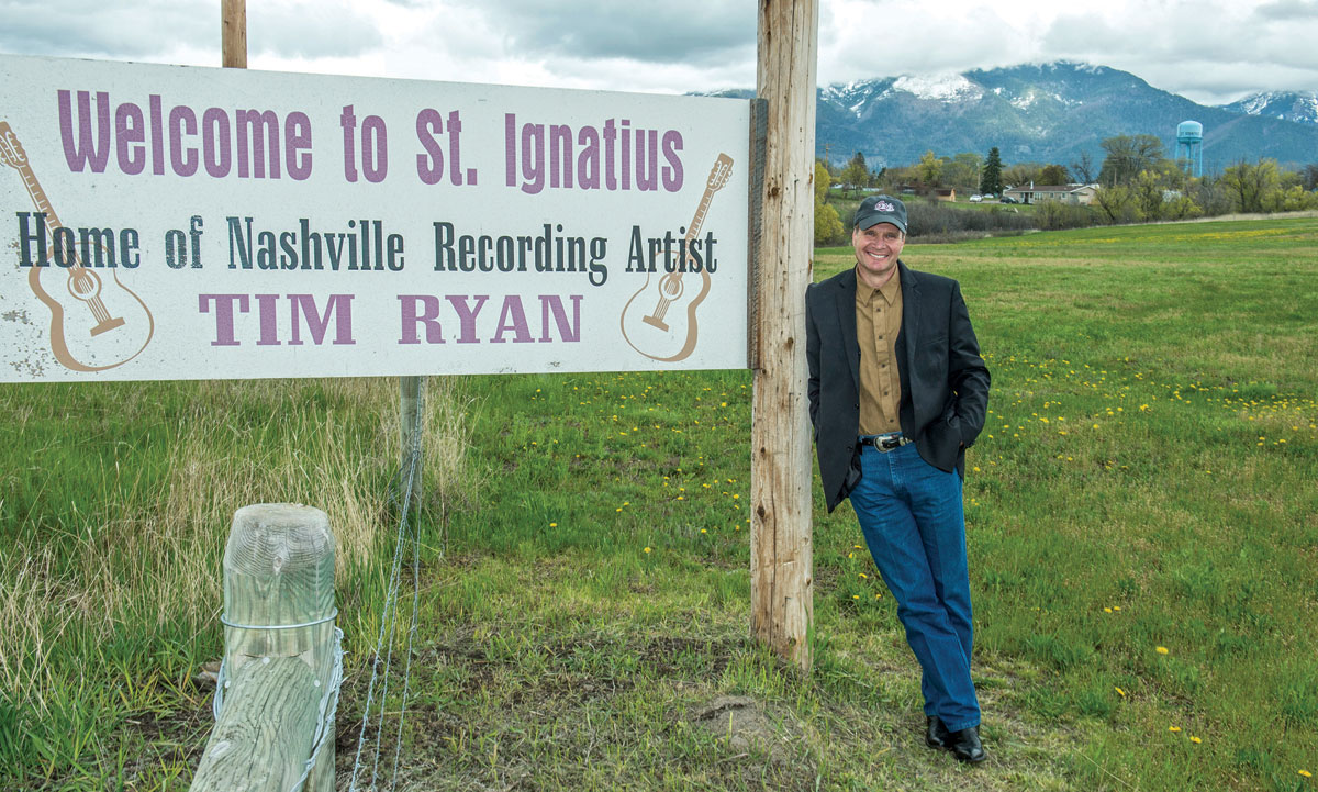 Ryan leans against a road sign heading into his hometown of St. Ignatius, which sits at the base of the Mission Mountains. (Photo by Todd Goodrich)