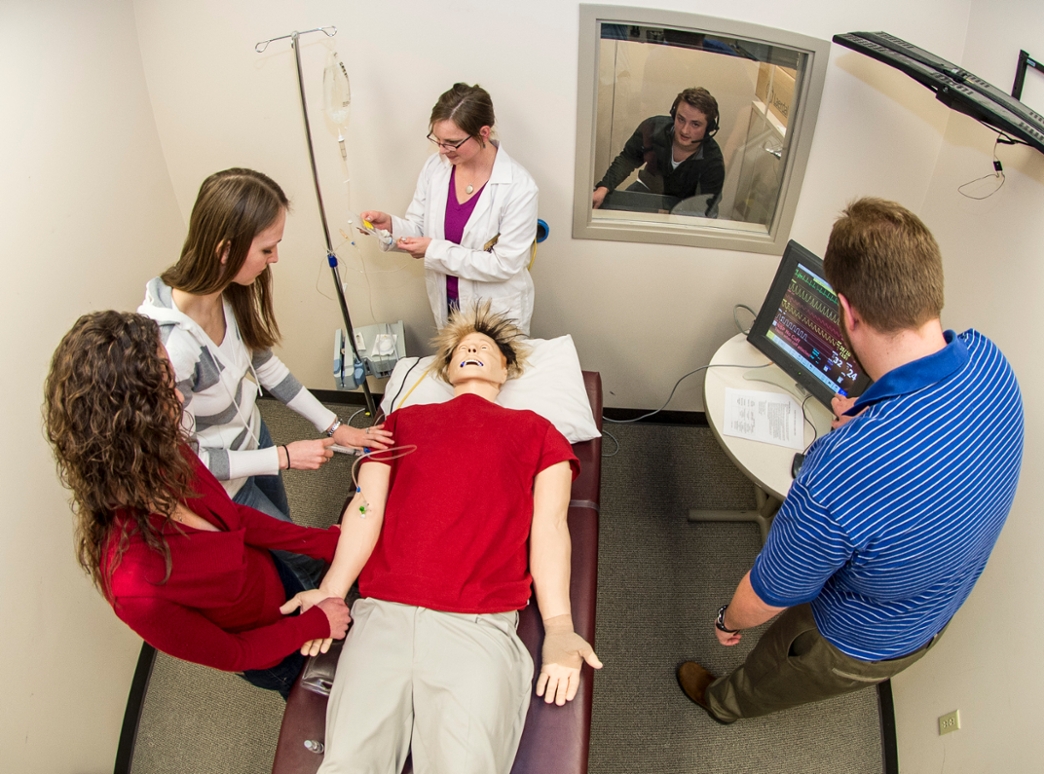 A group of pharmacy students in an elective course work on “Sim Man,” a computerized dummy that tests students by being programmed with different health scenarios.