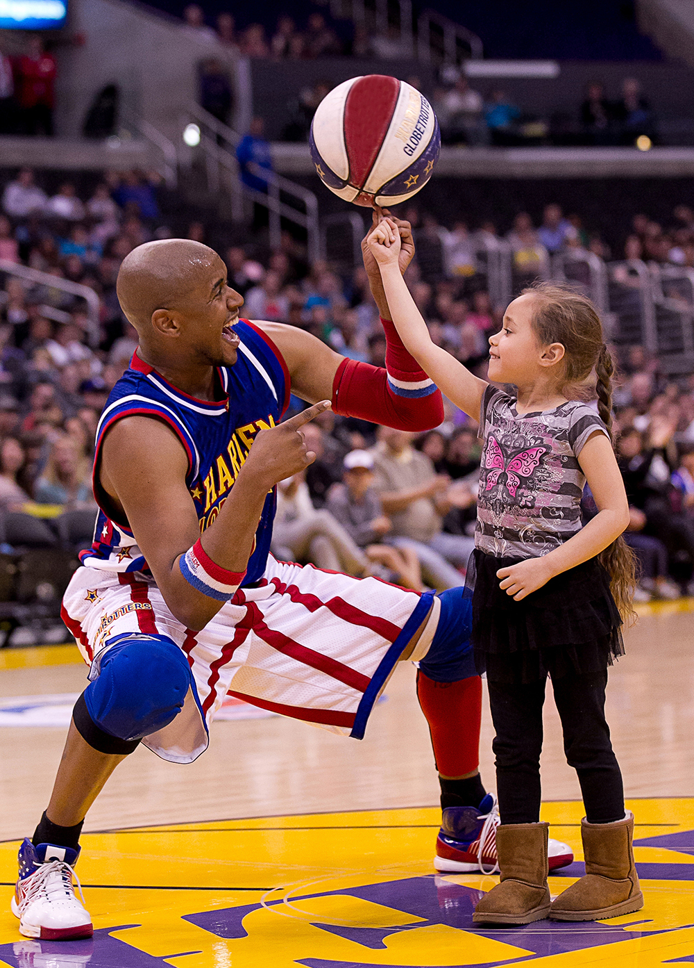 Shane “Scooter” Christensen helps a young fan spin a basketball on her finger at the Staples Center in Los Angeles. (Photo by Harlem Globetrotters International, Inc.)