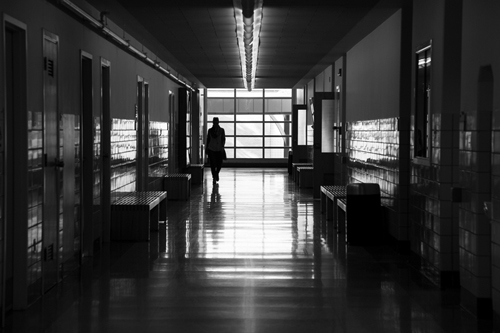 black and white photo of student walking the hallway of the education building at UM