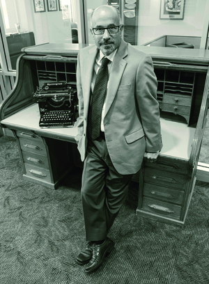 New J-school Dean Larry Abramson stands next to what’s believed to be Dean Stone’s desk. (Photo by Todd Goodrich)
