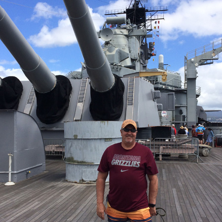 Brian Lilletvedt, ’75, J.D. ’78, represents Griz Nation under the big guns on USS Battleship Missouri at Pearl Harbor this past March. 