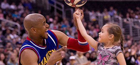 Christensen helps a young fan spin a basketball on her finger at the Staples Center in Los Angeles. (Photo by Harlem Globetrotters International, Inc.)