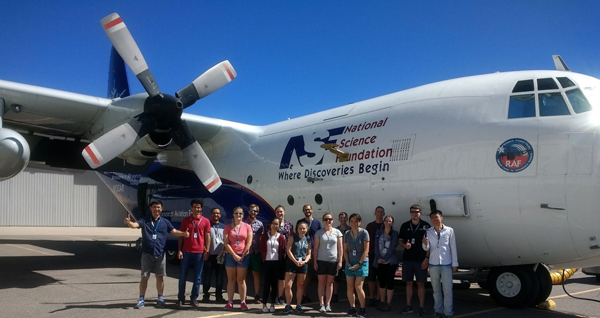 Students and researchers stand outside a plane that contains a laboratory.