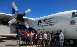 Students and researchers stand outside a plane that contains a laboratory.